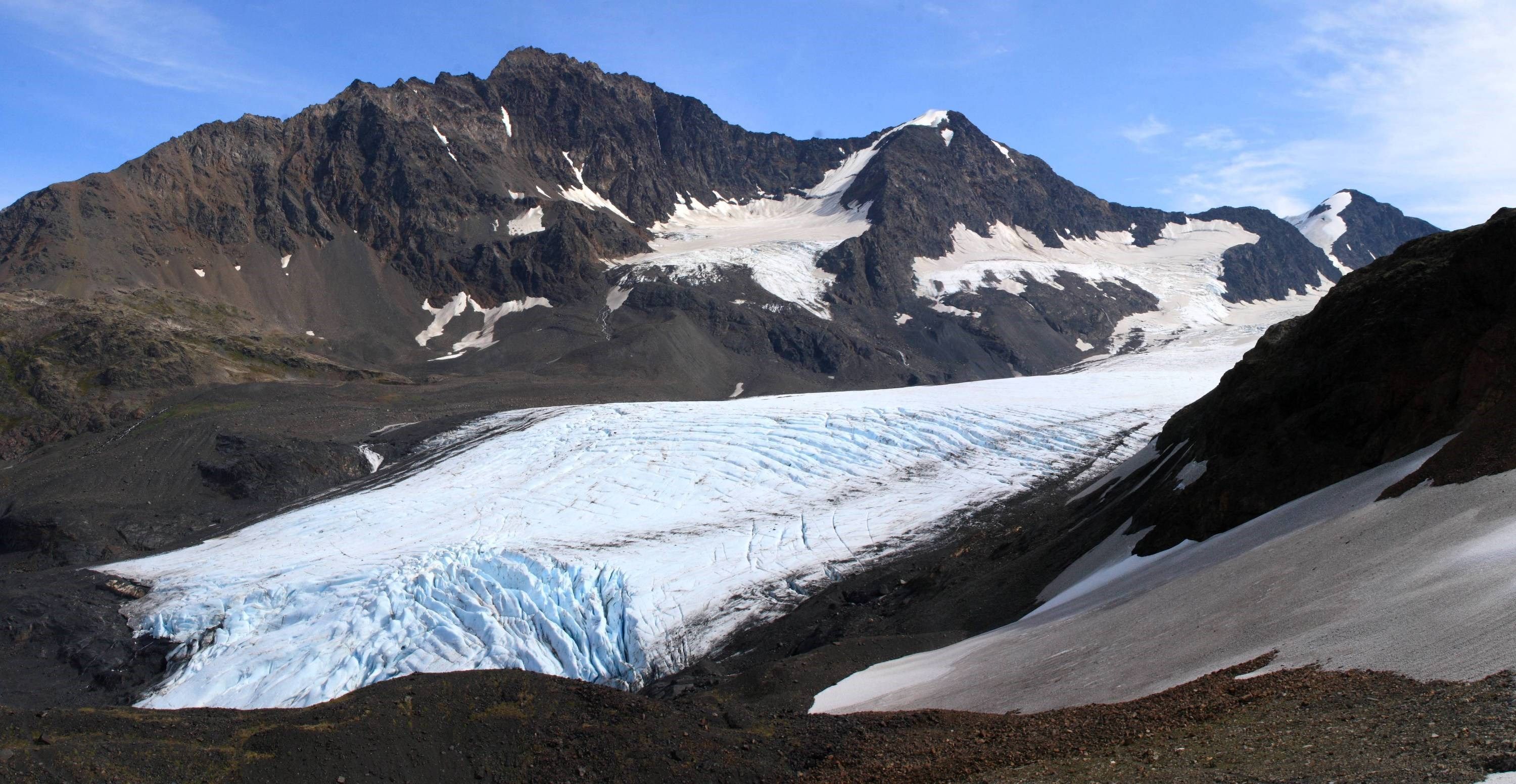 A glacier with a rugged mountain backdrop.