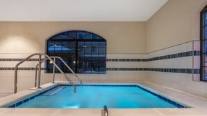 Piscina con escalera metálica y vista a un edificio a través de un amplio ventanal de arco.