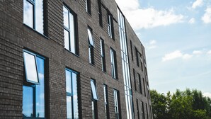 Een modern gebouw met veel ramen en een bakstenen gevel.