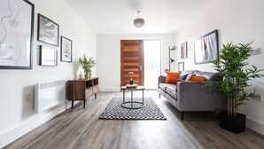 Een moderne woonkamer met een grijze bank, een houten kast en een zwart-wit kleed.