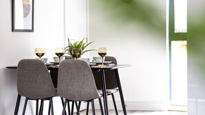 Een eethoek met een tafel voor vier personen, met een vaas met een plant, twee wijnglazen en een schaal.