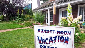 Schild für Sunset-Moon Vacation Rentals vor einem Haus mit Garten.