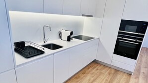 Eine moderne Küche mit weißen Schränken, einer schwarzen Arbeitsplatte, einem Spülbecken, einem Toaster und einem Backofen.