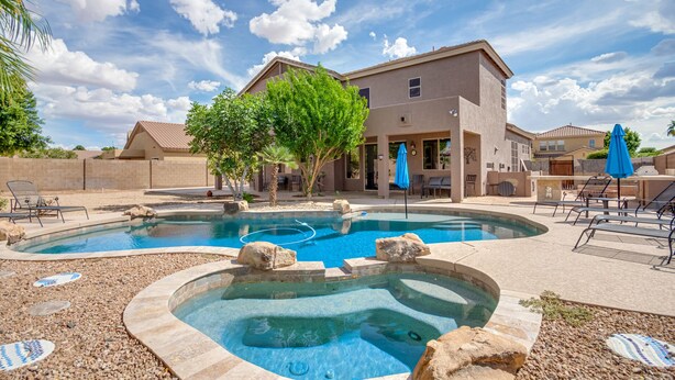 Propiedad residencial con piscina, jacuzzi y patio amoblado con sillones y sombrillas.