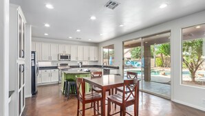 Una cocina moderna con armarios blancos, electrodomésticos de acero inoxidable y una isla central con taburetes.