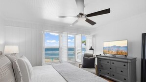 Ein Schlafzimmer mit Bett, Kommode, Fernseher und Blick auf den Strand.