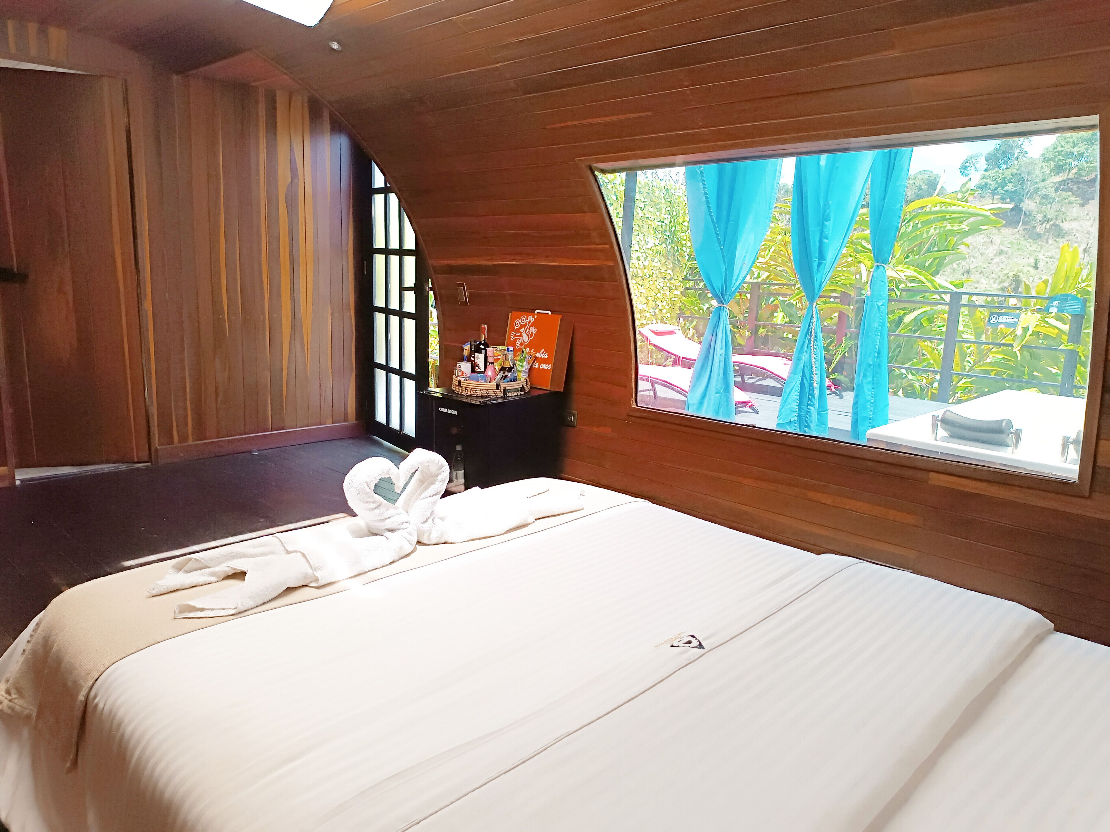Habitación de hotel con una cama grande, un minibar y vistas al exterior.