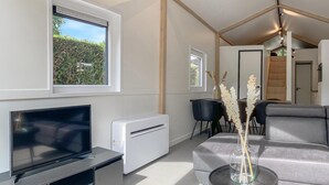 A modern living room with a flat-screen TV, a white radiator, a grey sofa, and a small table with a vase. - Awesome home in Putten with WiFi (Putten)