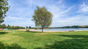 A park with a grassy area, a swing set, and a lake with boats. - Awesome home in Putten with WiFi (Putten)