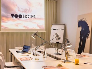 A conference room with a laptop, multiple desk lamps, a projector screen displaying 'TOO HOTEL', and a sign that reads 'TOO MEETING'. - Too Hotel & Spa Paris - MGallery Collection (Paris)