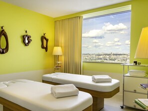 A hotel room with two beds, a city view, a lamp, and a bedside table with books. - Too Hotel & Spa Paris - MGallery Collection (Paris)
