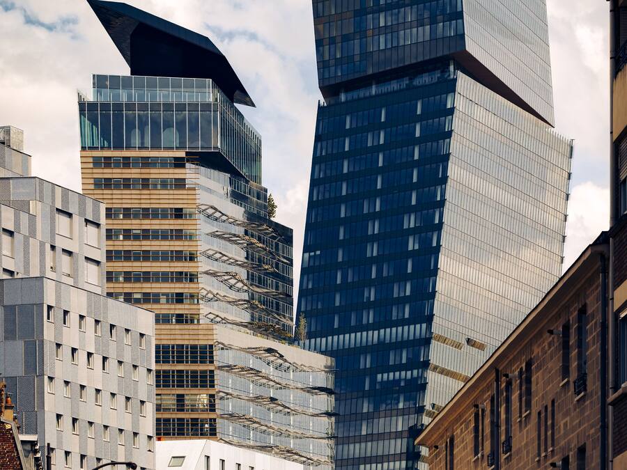 Un paisaje urbano moderno con edificios altos, incluyendo un rascacielos distintivo en forma de espiral y un edificio tradicional con fachada de ladrillo.