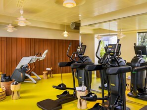A gym with exercise equipment, wooden flooring, and a yellow wall. - Too Hotel & Spa Paris - MGallery Collection (Paris)