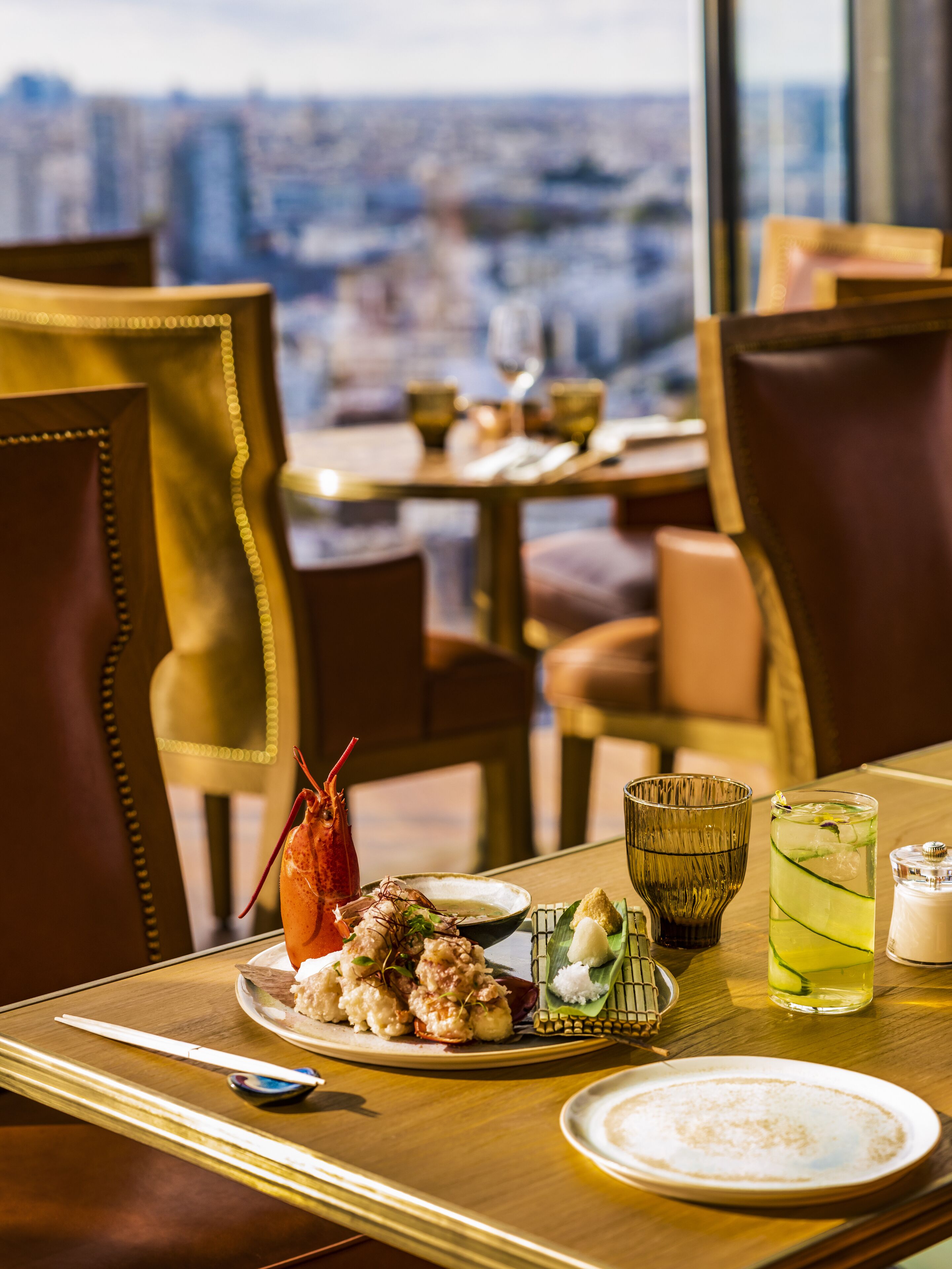 Ein Esstisch mit Mahlzeit, darunter Meeresfrüchte und einem Getränk, in einem Restaurant mit Blick auf die Stadt.