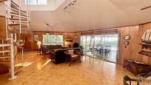 Un salón amplio con suelo de madera, un sofá, una silla, una mesa y una escalera.