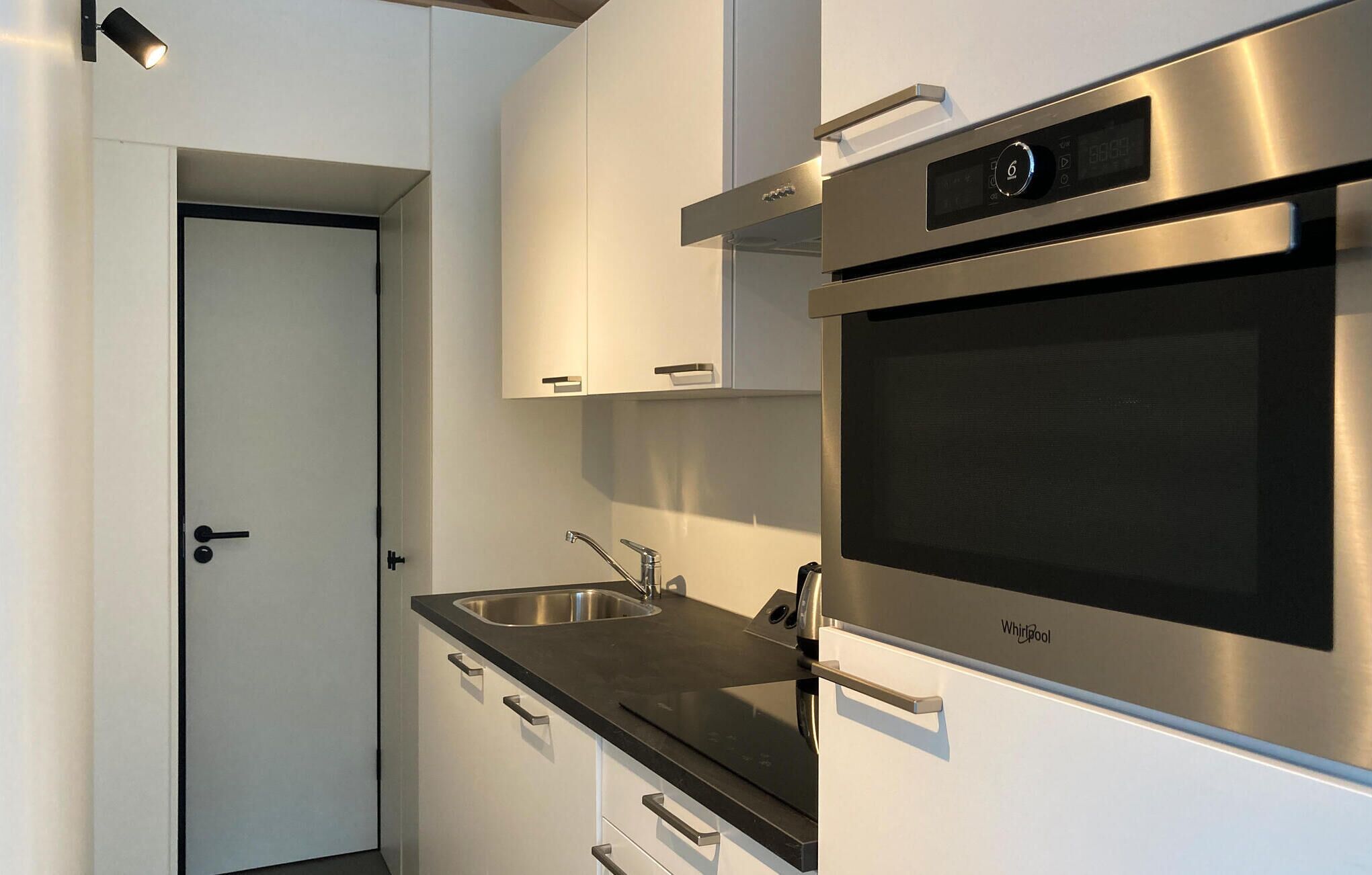 Una cucina moderna con elettrodomestici in acciaio inossidabile, forno integrato e lavello.