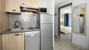 A compact kitchen with a dishwasher, microwave, and refrigerator.