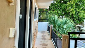 A covered corridor with a tiled floor, black doors, and hanging pendant lights. - Habitaciones Colonial Zaci (Valladolid)