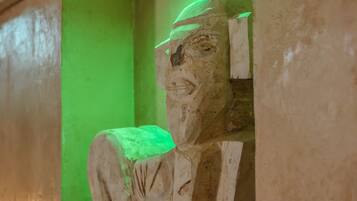 Una estatua de piedra de una figura sentada en un nicho con iluminación verde.