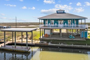 A house with a porch, a covered deck, and a small dock extending into a body of water. - Boat Dock Access: Waterfront Freeport Home! (Freeport)