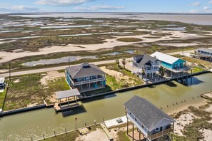 A coastal property with multiple buildings, including a large house with a balcony and a smaller structure with a covered patio. - Boat Dock Access: Waterfront Freeport Home! (Freeport)