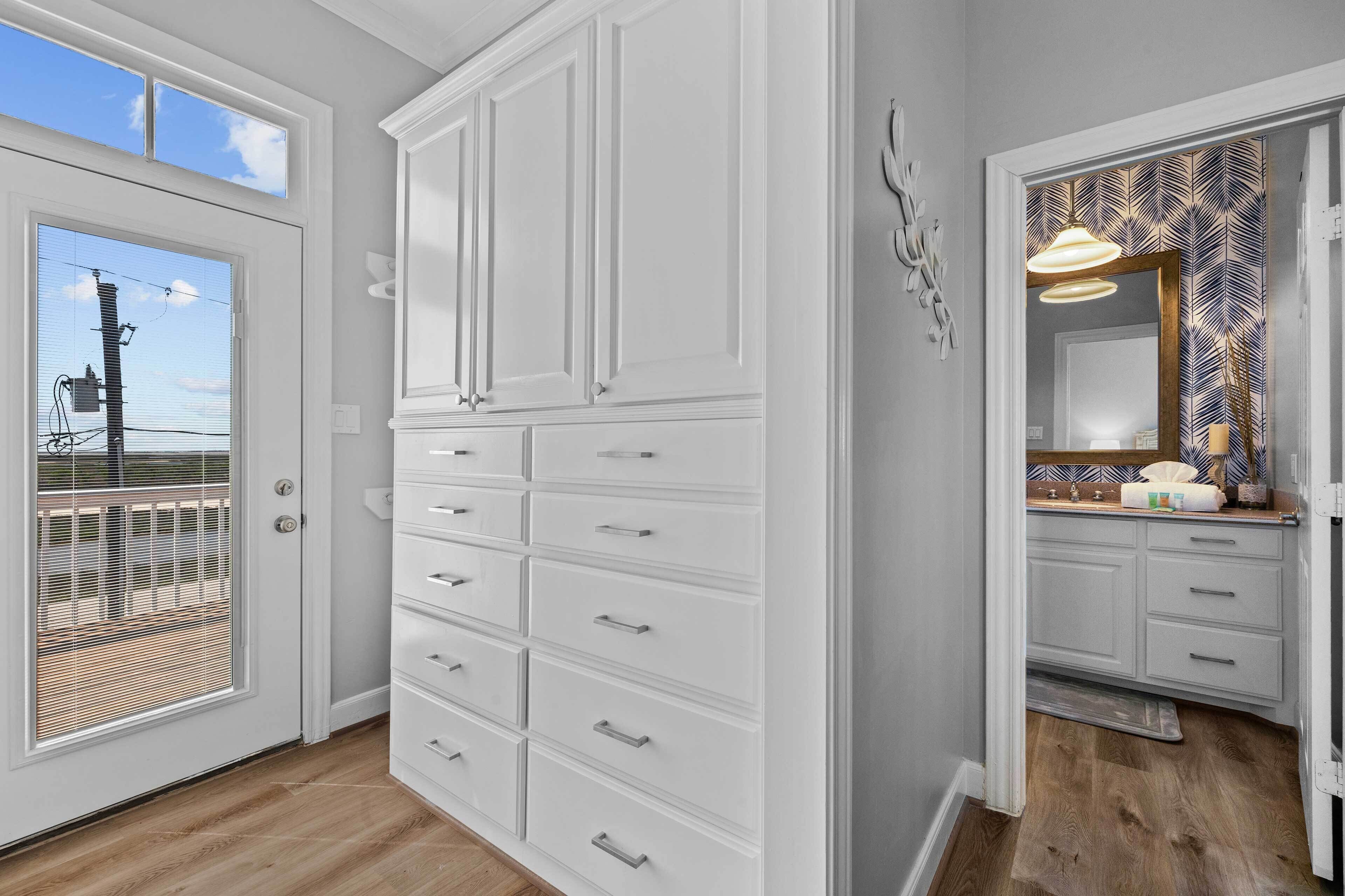 Un baño con muebles blancos, un espejo grande y una cortina de ducha estampada.
