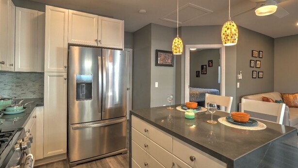 A modern kitchen with stainless steel appliances, a dining area with a table and chairs, and pendant lighting.