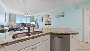 A modern kitchen with granite countertops, a stainless steel sink, and a built-in dishwasher. - Enclave 803 - is a Family Friendly Beach Front condo! (Orange Beach)