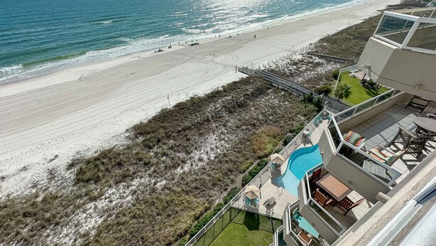 A beachfront hotel with a swimming pool, outdoor seating, and a view of the beach and ocean. - Enclave 803 - is a Family Friendly Beach Front condo! (Orange Beach)