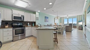 A modern kitchen with white cabinets, stainless steel appliances, and a large island. - Enclave 803 - is a Family Friendly Beach Front condo! (Orange Beach)