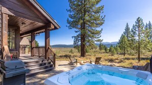 Una cabaña de madera con jacuzzi y mobiliario exterior.