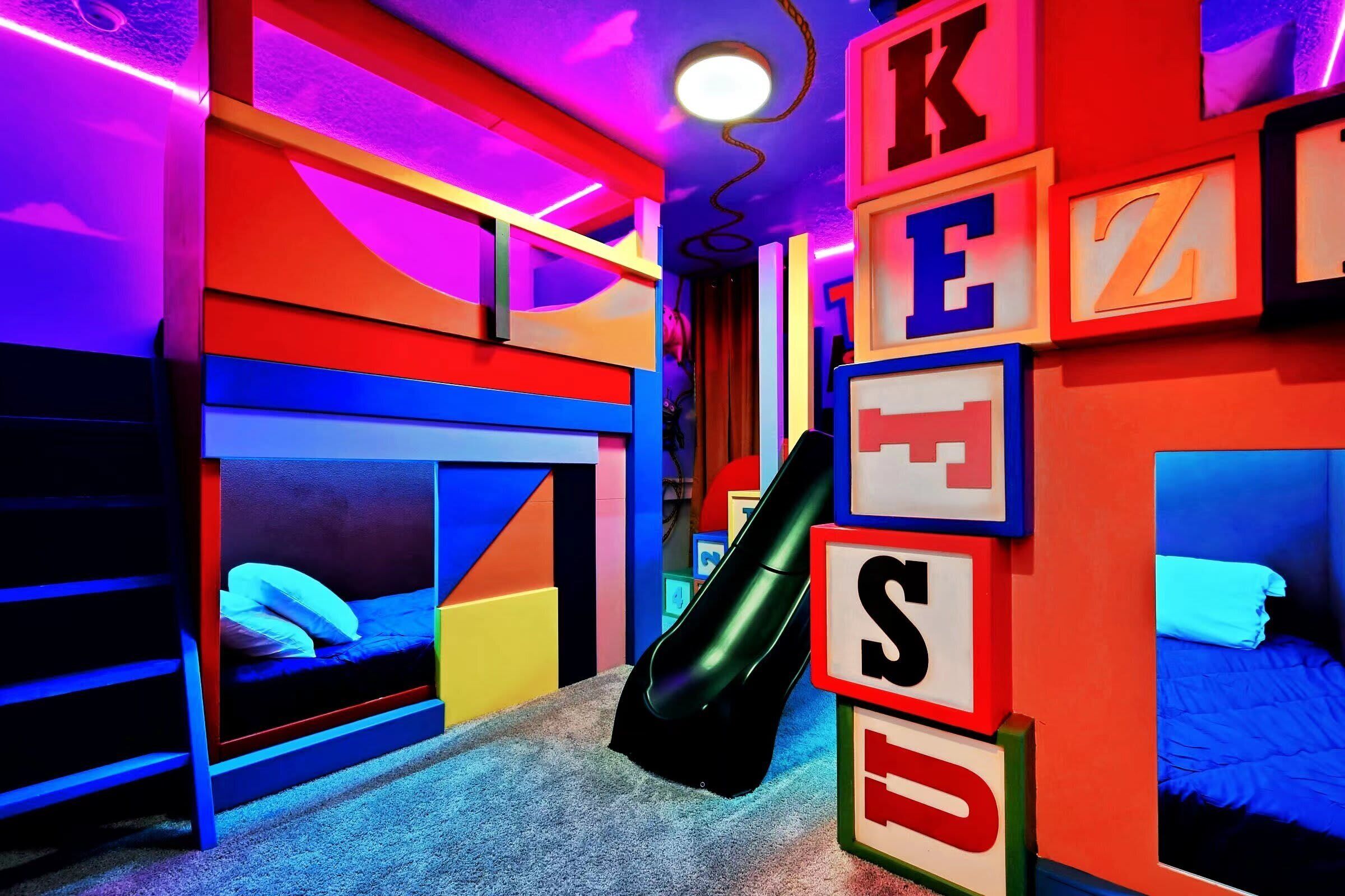 Une chambre avec des lits superposés, des murs aux couleurs vives et un aspirateur.
