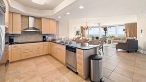 Un'ampia cucina con una grande isola, elettrodomestici moderni e vista all'esterno.
