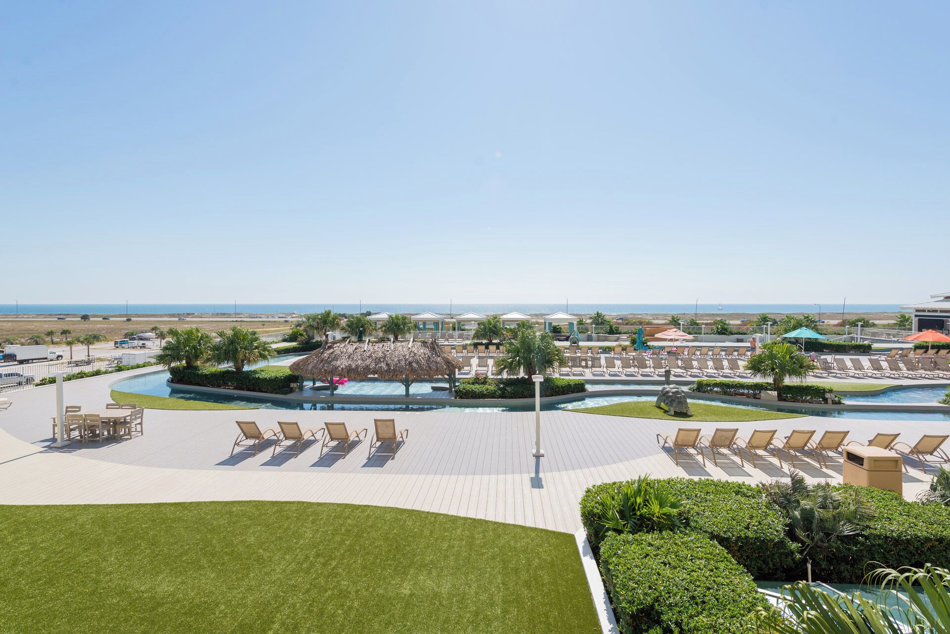A resort with a pool area, lounge chairs, and a view of the beach.