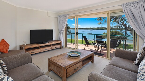 A living room with a flat-screen TV, wooden coffee table, and grey sofas. - PICNIC7- PICTURE PERFECT PICNIC POINT (Maroochydore)