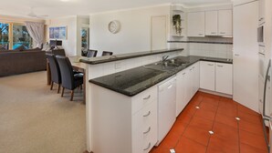 A compact kitchen with white cabinetry, a black countertop, and a tiled floor. - PICNIC7- PICTURE PERFECT PICNIC POINT (Maroochydore)