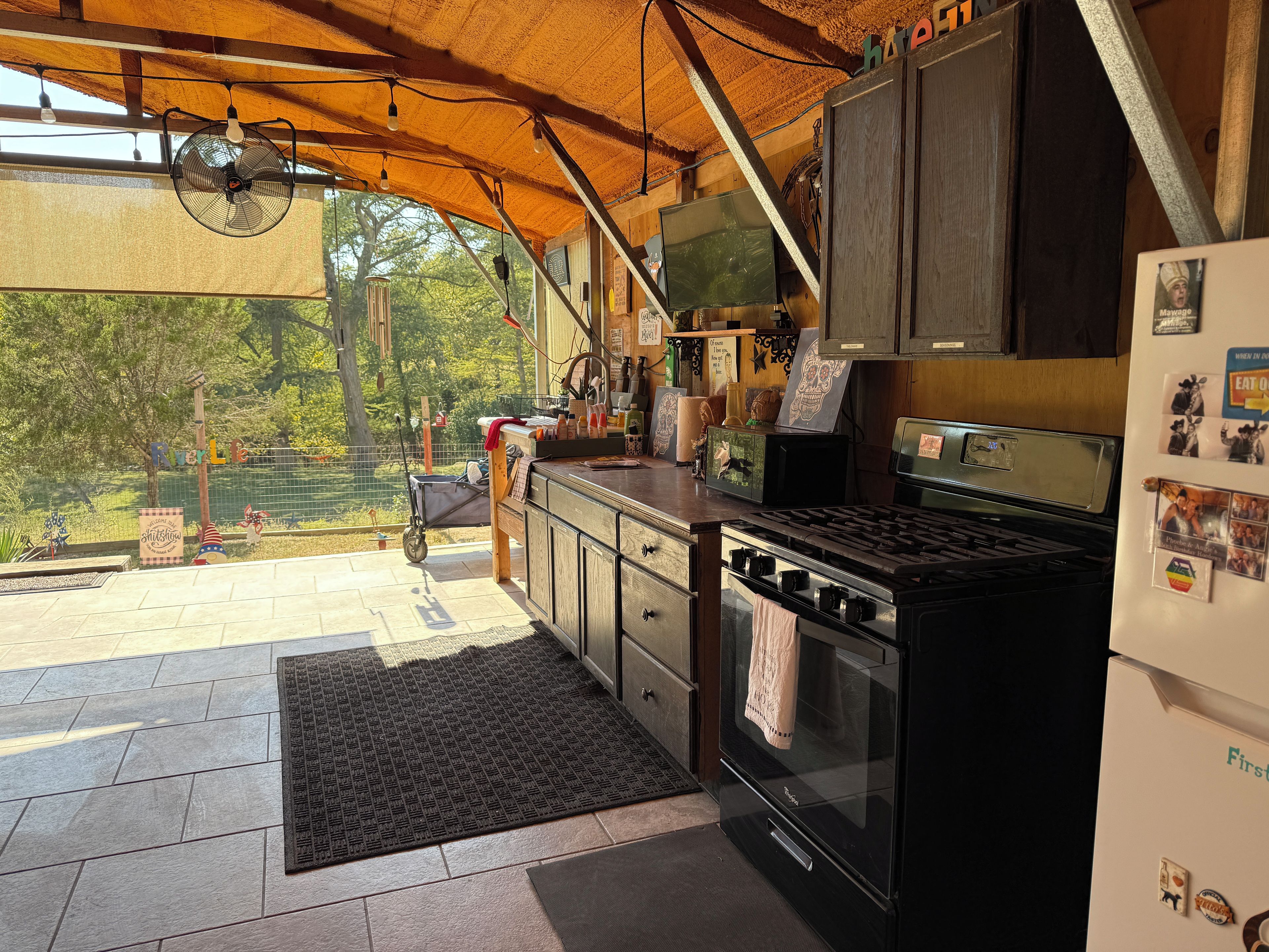 A kitchen with a stove, refrigerator, and a view of the outdoors.
