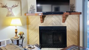 A cozy living room with a fireplace, a television mounted above it, and a sofa. - Family Friendly Pines Condo-3b/2b (Pinetop-Lakeside)