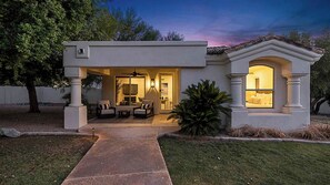 A modern house with a patio, outdoor seating, and a well-lit interior. - Manor Retreat - Pool, Spa & Pickleball Villa in Paradise Valley (Paradise Valley)