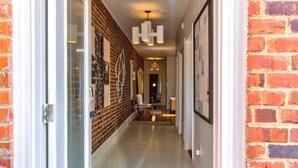 A hallway with a brick wall, a glass door, and a tiled floor. - artsy downtown river view condo (Wilmington)