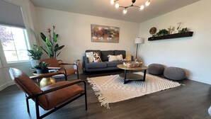 A living room with a sofa, coffee table, and two chairs. There is a plant, a painting, and a shelf with decorative items. - Enjoy a stylish experience at The Franklin (Pasco)