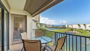 A balcony with a glass table and chairs, overlooking a pool and a view of the ocean. - 2BR/2BA Beach front Sleep8 Balcony-Gated Community (Panama City Beach)