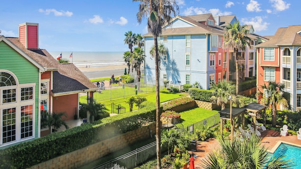 En ejendom ved stranden med farverige huse, en swimmingpool og en velholdt have.
