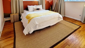 Une chambre moderne avec un grand lit, un plancher en bois et de grandes fenêtres.