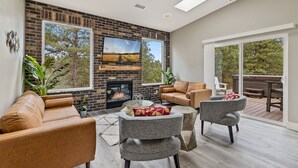 A modern living room with a fireplace, large windows, and a deck area.