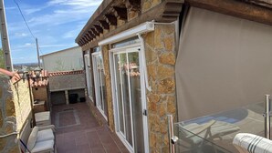A rooftop terrace with stone walls, a glass table, and a view of the city. - cozy guest house  (Navas del Rey)