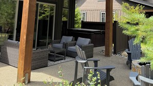 A covered outdoor seating area with wicker furniture and Adirondack chairs. - FAll in Suncadia! Walk to the new Suncadia social & Golf! Hot Tub and Games! (Cle Elum)