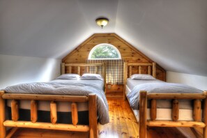 A cozy attic bedroom with two wooden bunk beds, a skylight, and a wooden ceiling. - Lookout Cabin - Shared waterfront on Rangeley Lake! (Rangeley)