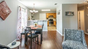 A modern kitchen with wooden cabinets, a stainless steel oven, and a dining area with a table and chairs. - Clean+Cozy+Close to Airport/Jackson/Dogwood Ctr! (Brandon)