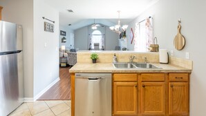A modern kitchen with wooden cabinets, a stainless steel refrigerator, a dishwasher, and a large island with a sink. - Clean+Cozy+Close to Airport/Jackson/Dogwood Ctr! (Brandon)